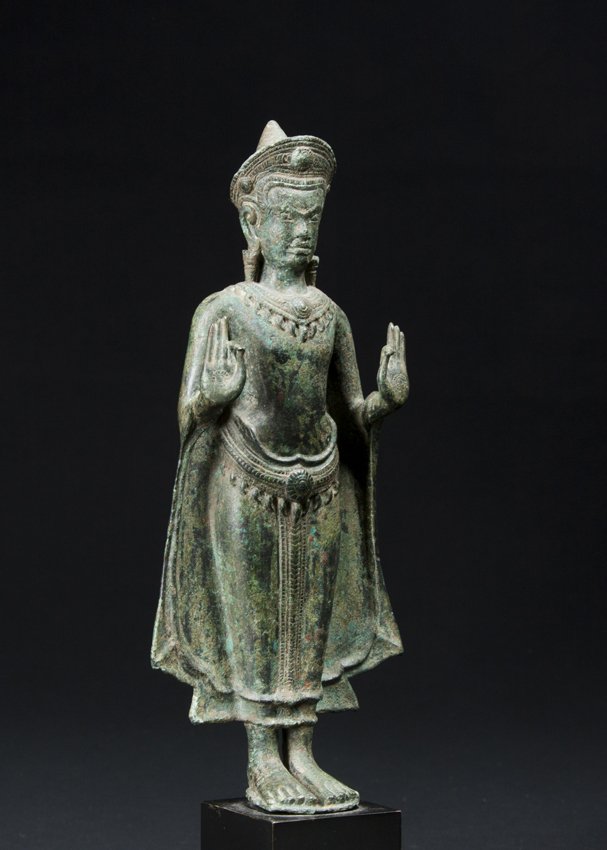 12th/13th Century Fine Cambodian standing Buddha, Khmer: A fine Cambodian standing Image of the Buddha, Khmer, 12th-13th Centuries, standing with both hands in Vitarka Mudra, the figure with diaphanous robes and high coif with powerful face. Chased ornament