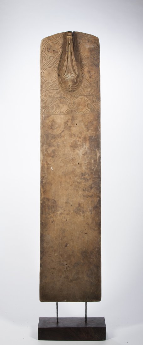 A fine Huon Gulf swimming board, New Guinea: North Coast, Papua New Guinea; H: 55 1/2" The board with the lower two thirds undecorated, the top with a long snouted face and typical scrollwork. The designs well integrated about the central raised