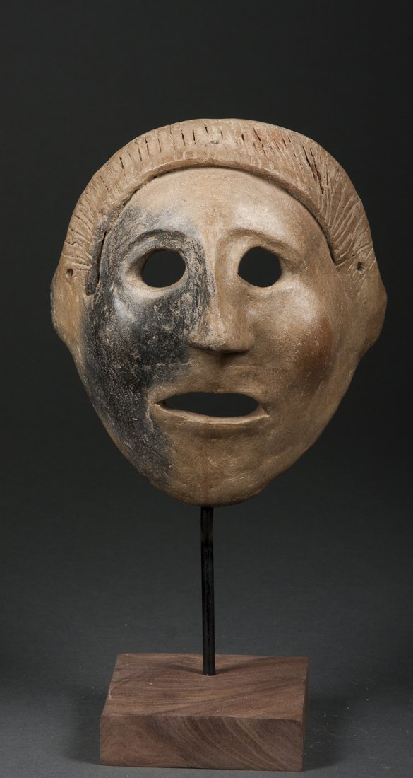 A fine Narino mask, 1000 - 1500 AD: Nariño, Ecuador/Colombia; H: 6 3/4"The mask with a firing cloud over proper right side, the face with wide eyes, simple nose and expressive mouth, the coif incised. Expressive example of the ty