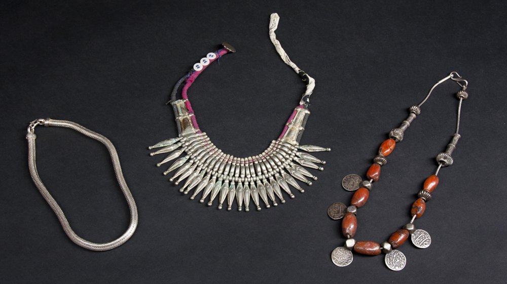 Three Indo-Himalayan Necklaces: Three Indo-Himalayan Necklaces. The first a Tharu necklace with twenty-six pendent drops on heavy fabric, 8"; the second an Indian or Nepalese necklace of carnelian and coins 22"; the third an Indian 