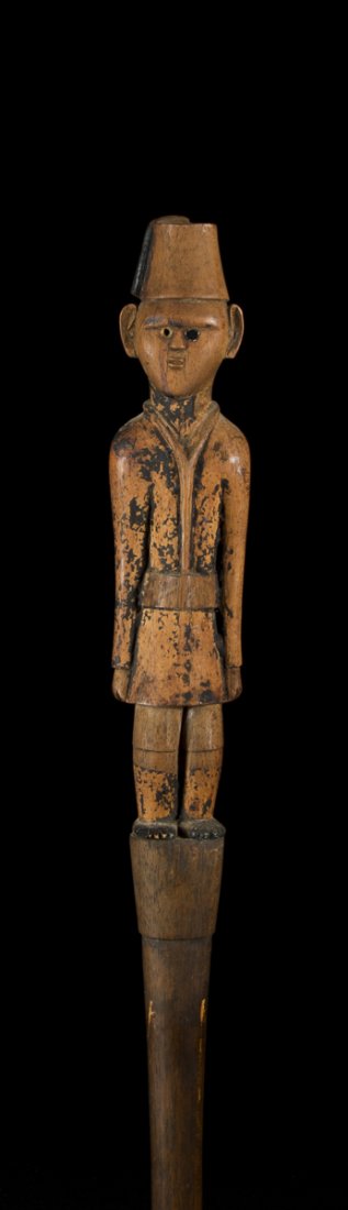 A fine and old Southern or Eastern African staff: A fine and old Southern or Eastern African staff. South East Africa H: 50". The staff topped by a figure in dressed in colonial military clothing, wearing a fez and jacket with shorts. Remains of blac