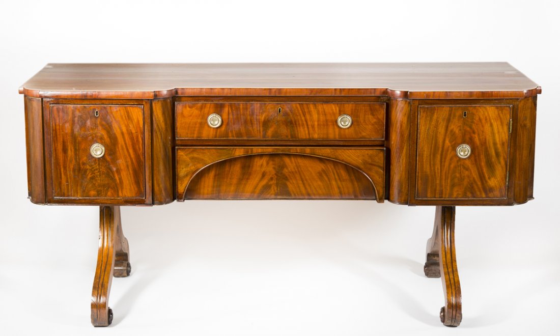 Regency Mahogany Sideboard: Regency Mahogany Sideboard, a rectangular case woth a block front and having two central drawers flanked by a cupboard on the right and deep bottle drawer on the left, all supported by reeded scrolled