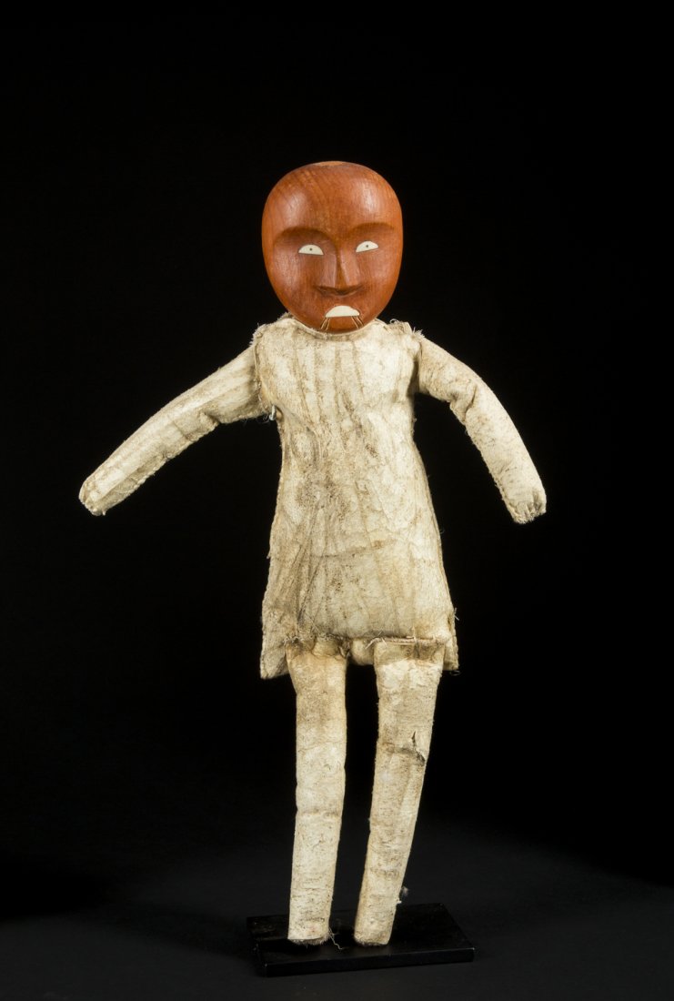 A fine and rare Inuit Mortuary doll: A fine and rare Inuit Mortuary doll, Inuit ; Alaska The figure of unusual form, the head carved from cedar with inlaid eyes and mouth, and deep concave facial plains; traditional scarification below t