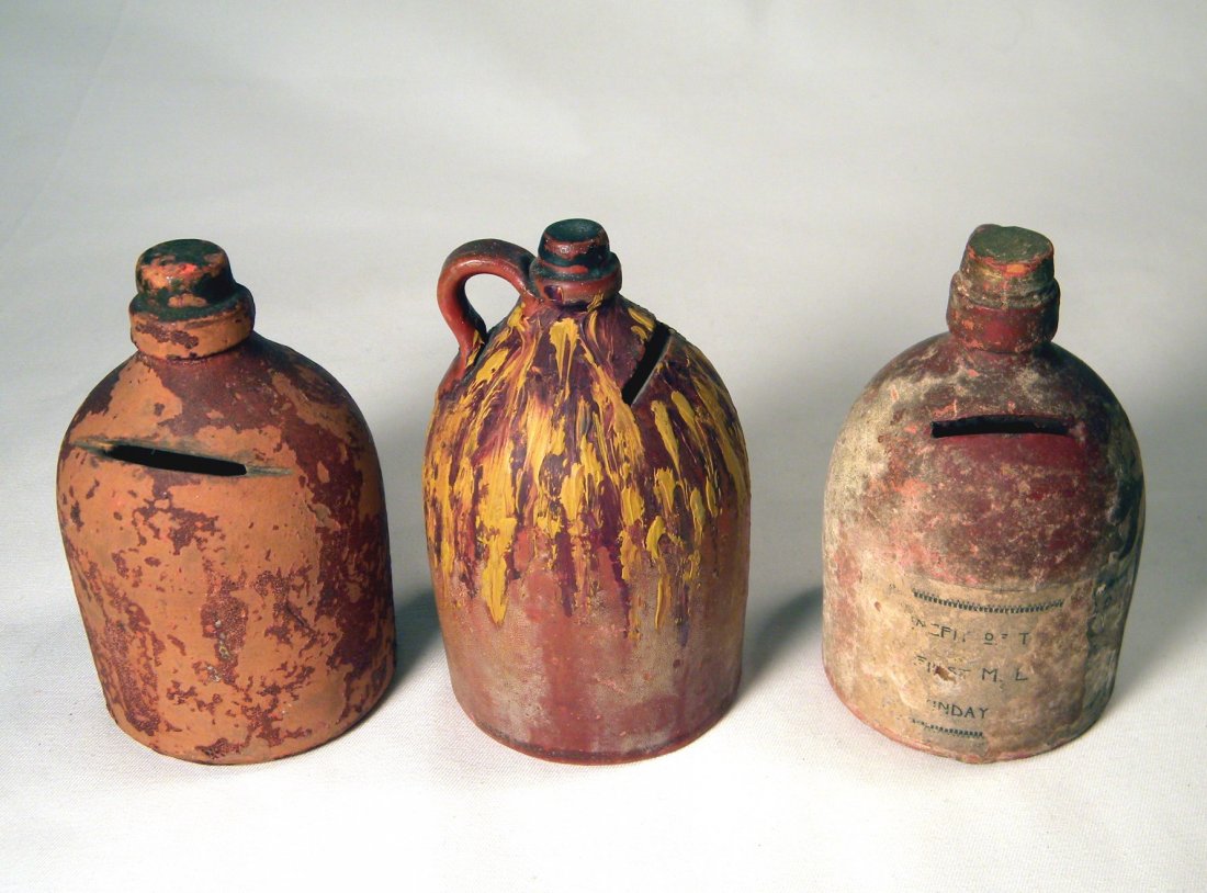Lot of Three Earthenware Pottery Banks: Lot of 3 early earthenware pottery banks; center jug is beautifully painted, right jug has partial paper label, and left jug has chip on mouth.