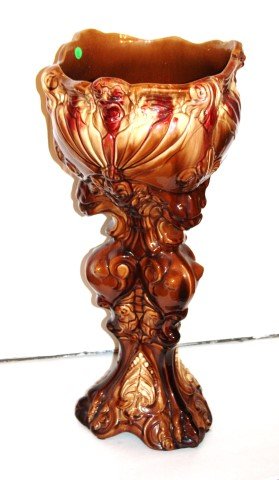 Majolica Pedestaled Jardiniere: One(1) piece glazed pottery jardiniere. Lion's head base rises to a leaf form planter. Some chips; 28in. H. x 13.75in. W.