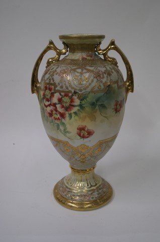 Nippon Porcelain Urn Vase: Ornate gilt and enameled pedestaled urn. Double handled with floral design. Marked at underside. Old repair at rim; 14in. H.