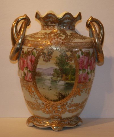 Large Nippon Porcelain Vase Signed: Hand painted and highly gilt decorated porcelain vase. Draped and ring handles. Painted with swans on a lake. Marked at the underside; 12in. H. x 9in. W. (as is with age line on rim)