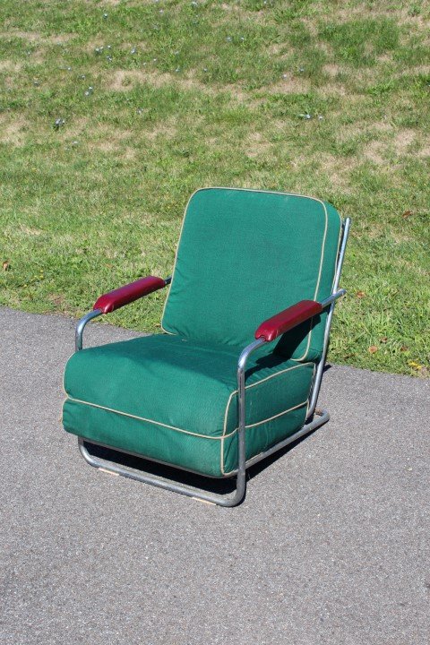 Lloyd Rock-A-Feller Mid Century Lounge Chair: Tubular chrome lounge chair. Orange vinyl upholstered seat and back with fitted slip covers.Red vinyl arm rests. Metal number tag 323357; 27.5in.H. x 24.5in.W.