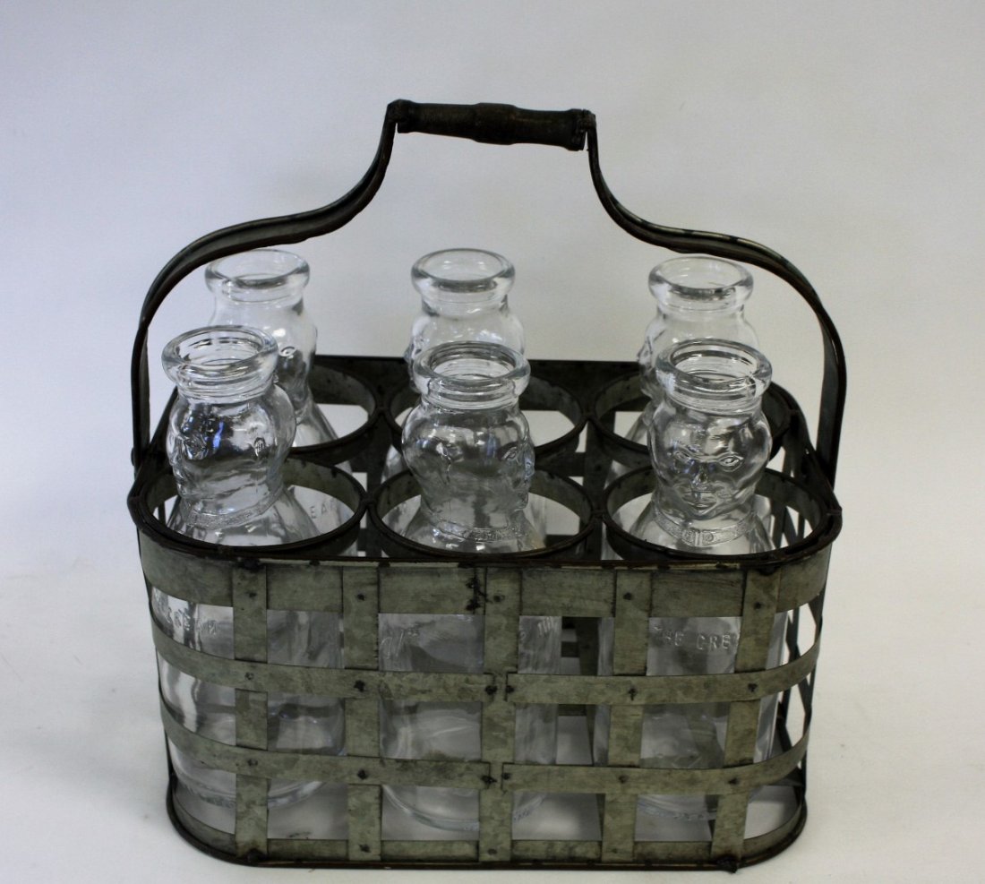 Whimsical Milk Carrier and Bottles: Metal milk carrier. Six(6) figural glass bottles. Bottles have moulded inscription reading "Whips Cop the Cream"; 11in.H. x 14.5in.W.