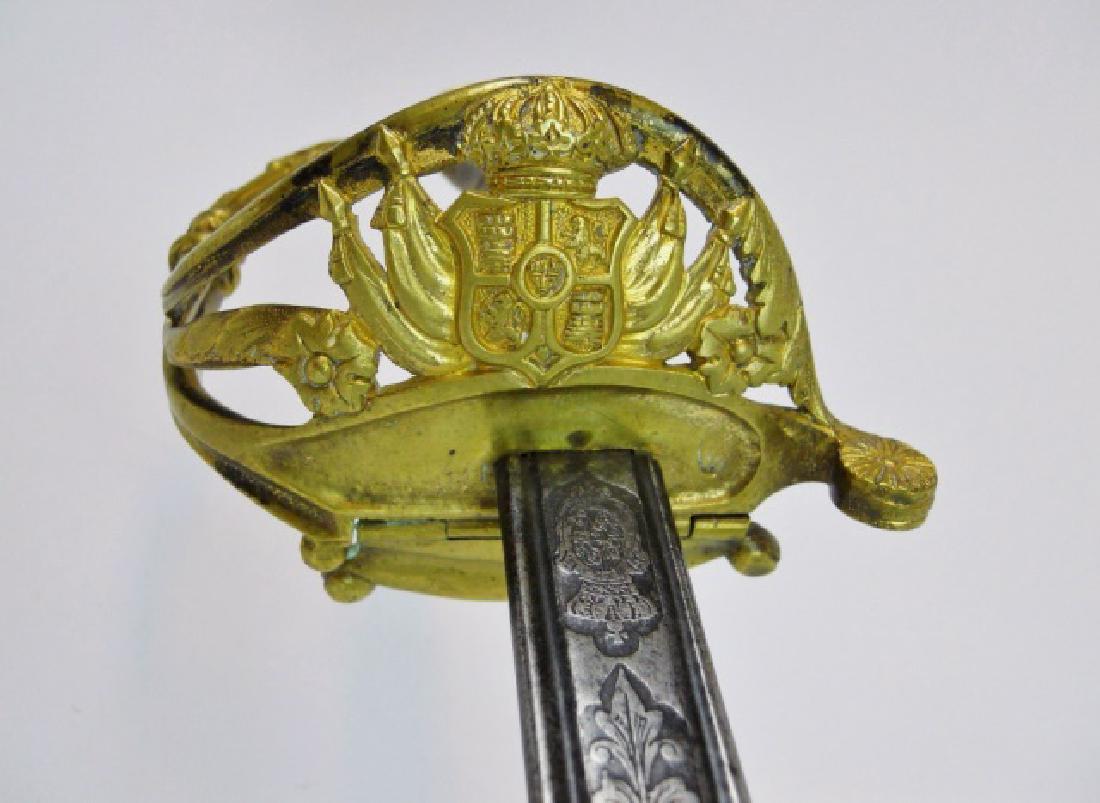 Spanish M1868 Infantry Officer Sword, 1869 Date: 19th C. Spanish M1868 Infantry Officer sword. Gilt brass hilt with hinged half guard, reticulated Spanish Arms and foliate decoration, wire wrapped shagreen grip. Double etched curved steel blade with