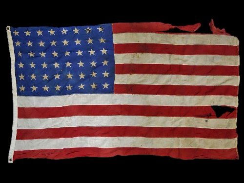 WW2 USMC Battle Flag with Guam Provenance: WW2 Original US Marine Corps battle flag belonging to Gilbert L. Weber USMC and flown over Guam. Flag with sewn stripes and screen printed stars. Hoist is signed in ink, "G. Weber, Guam 9-7-42". Flag