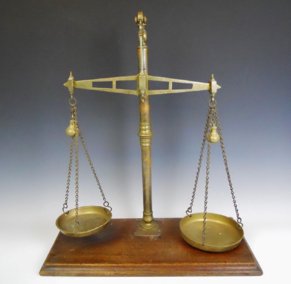 19th C. English Beam Scale, CWS, Manchester: Antique beam scale constructed of brass with oak base. Brass plaque affixed to base reads, "CO-OPERATIVE WHOLESALE SOCIETY LIMITED. MAKERS, BALOON ST, MANCHESTER." Scale measures 23.5" H. Base measure