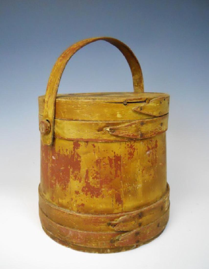 19th C. Firkin in Old Yellow Paint: Wooden firkin with lid and bent wood swing handle. Bucket with eight staves nailed lap bands and fitted cover. Old painted yellow over underlying red surfaces. Firkin measures: 9" H x 9.5" D