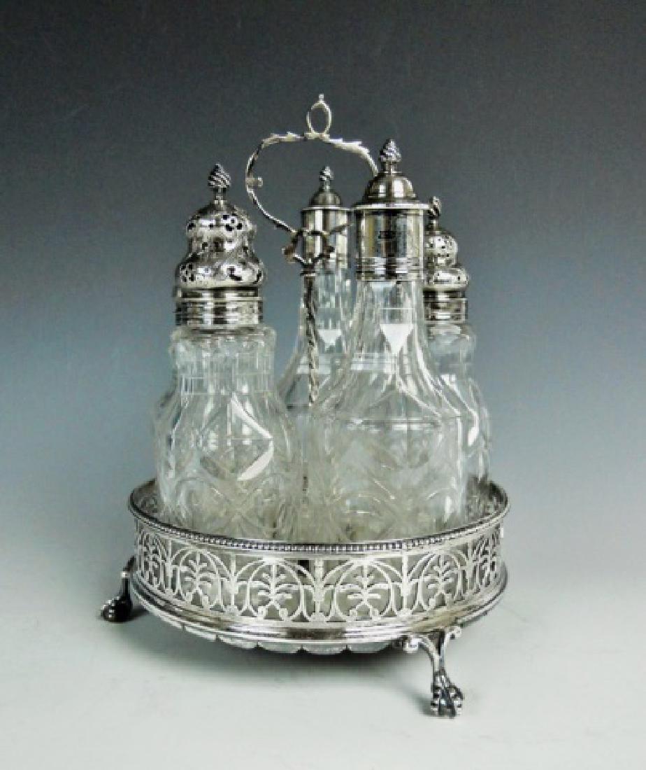 George III Silver Cruet Set, London, 1773: Six piece sterling silver cruet set, bearing illegible touchmark, with London and 1773 hallmarks. Silver tray form stand with reticulated foliate rail on tripod ball and claw feet. Cut glass inserts w
