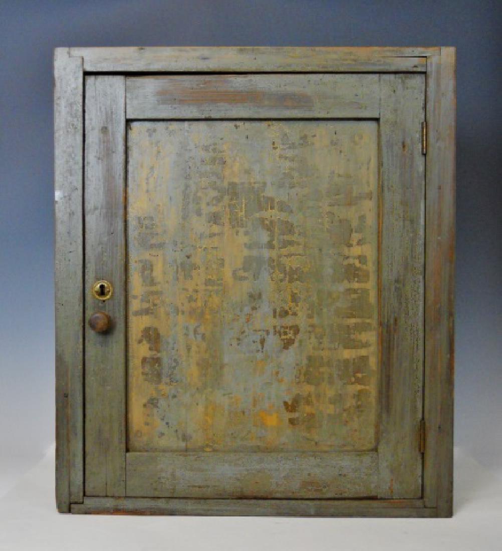18th C. Wall Cabinet in Old Paint: Cabinet constructed of pine with period grey painted surfaces. Dovetailed case with hinged chamfered door and two interior shelves. Cabinet measures: 23.75" H x 20" W x 8.75" D,