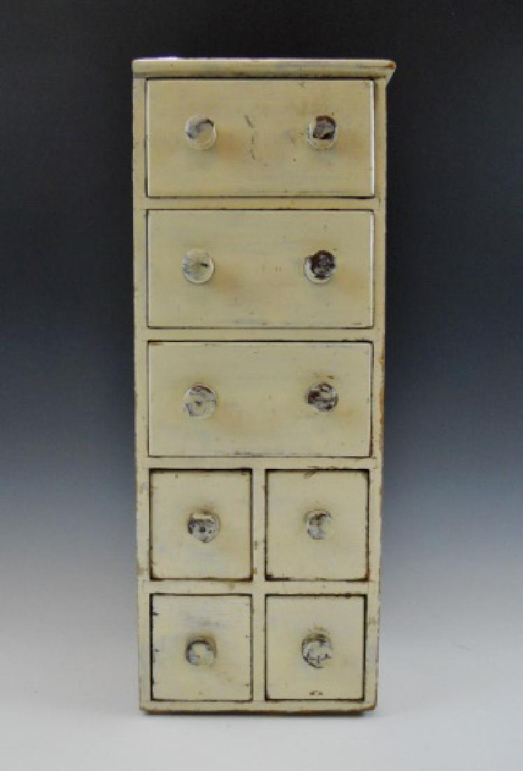 Antique Primitive Spice Chest in Old Paint: 19th C. hand-crafted, diminutive spice chest with old, painted surfaces. Constructed in pine with drawers in three over four configuration. White painted surfaces with wear, missing backboard. Measure