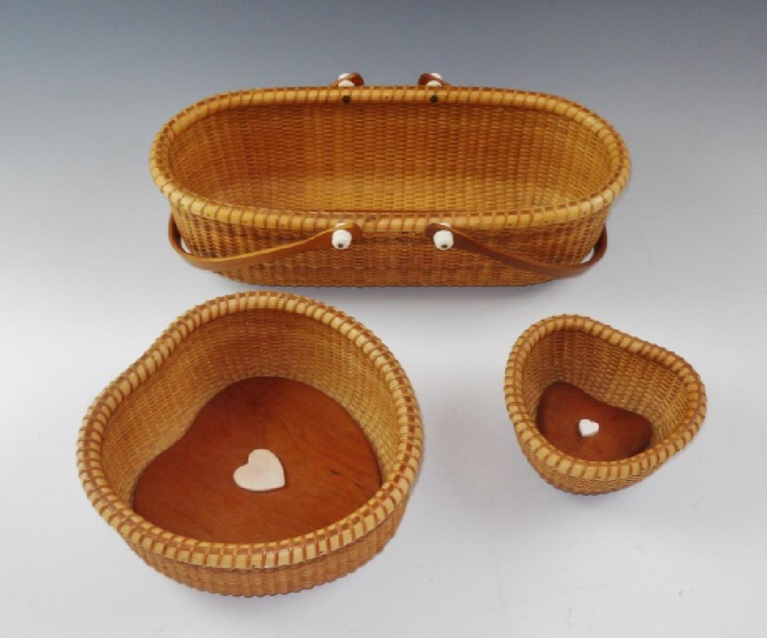 Collection Nantucket Baskets, Lisa Bessette, (3pc): Collection of three hand crafted contemporary Nantucket Baskets, signed "Lisa Bessette" and dated "2001" on base: (1) Oblong form basket with double swing handle, measures:4" H x 13.5" L, (2) Heart sh