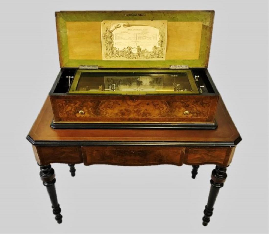 19th C. Swiss Cylinder Music Player, Troll & Baker: 19th C. cylinder music player integrated table. Case and table in burl and mahogany with satinwood band inlay and ebonized wood embellishment. Interior with glass covered cylinder music box, lid with