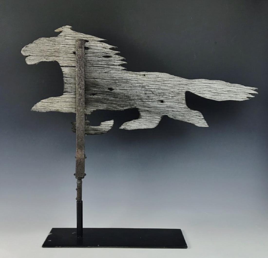Antique New England Running Horse Weathervane: New England wooden running horse weathervane with iron hardware. Primitive two-dimensional cut out with iron strap band affixed to shaft. Later metal base for display. Measures: 26" H on base, 29" L.