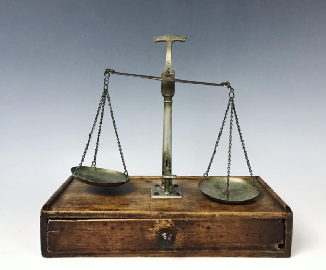 Antique Portable Beam Scale: Scale in nickel steel attached to wood box with single drawer accompanied by six brass weights. Measures: 9" H x 9.75" W.