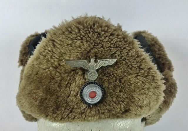 WW2 German Heer Winter Leather and Wool Field Cap: World War Two German Heer Winter field cap. Brown sewn leather construction with wool hem and earflaps. Pinned die struck metal eagle and cockade insignia. Interior lined in dark grey cloth. Excellent