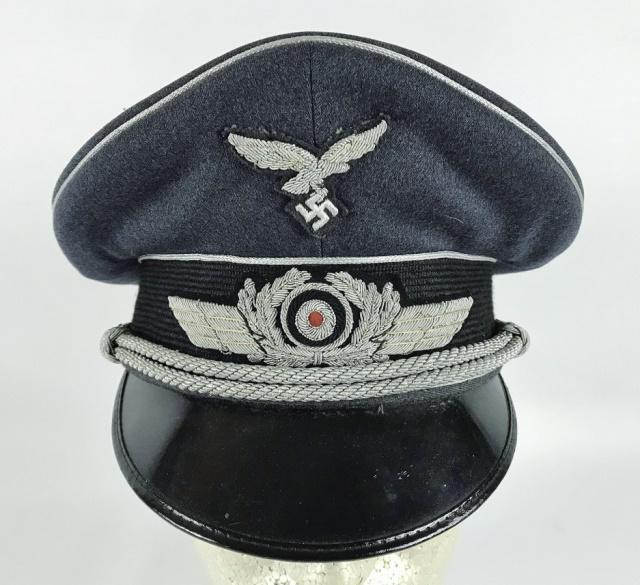 WW2 German Luftwaffe Officer Visor Cap: World War Two German Luftwaffe Officer visor cap. High quality blue - grey wool construction with mohair band, braided silver bullion piping, adjustable silver bullion chin cord secured with two non m