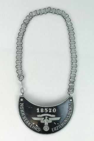 WW2 German NSKK Traffic Service Gorget: World War Two German NSKK Traffic Service Gorget. Aluminum plate with black painted surface with raised number "18570" over NSKK eagle, reads "N.S.K.K. VERKEHRS- ERZIEHUNGSDIENST" Reverse with attachm