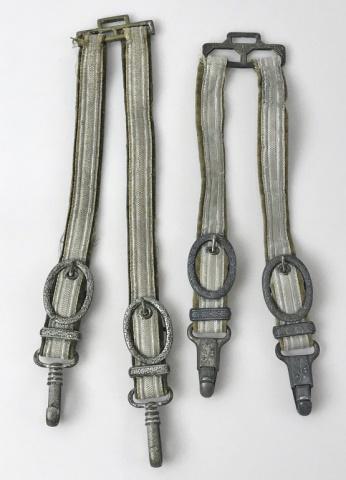 WW2 German Heer Officer Dagger Hangers, (2pc): Two World War Two German Heer Dagger Hangers: (1) Hangers constructed on velvet backed bullion ribbon straps with silver washed alloy oak leaf decorated buckles, swivel clips and hanger frame, (1) Han