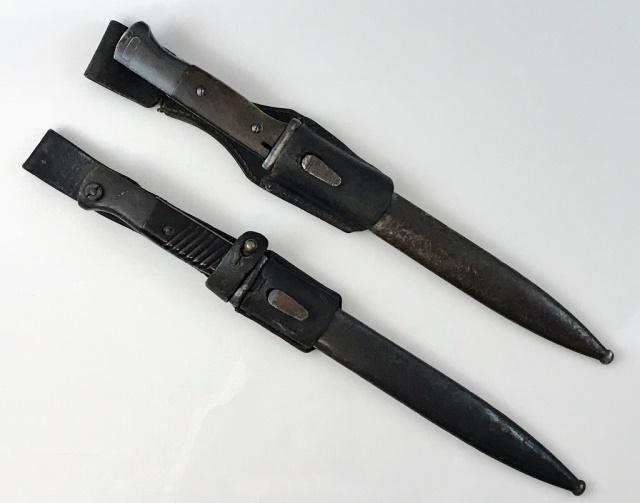 WW2 German K98 Combat Bayonets, (2pc): Two World War Two German K98 Bayonets. Bayonets with steel blades, guards and pommel, with wood and Bakelite grips. Numbers mismatched to steel scabbards, accompanied by leather frogs. Good condition 