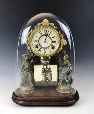 Antique Continental Figural Clock: Antique Continental Figural Clock. Eight -day time and strike key wind movement. Clock with Roman Numeral radial dial flanked by male and female figures in period dress. Clock on moulded wooden base w