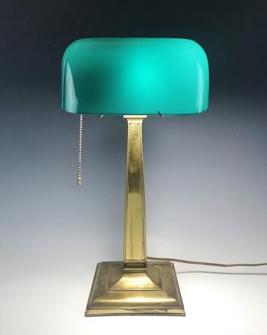 Antique Green Glass Desk Lamp, Emeralite: Antique Desk Lamp, signed "Emeralite Desk Lamp No. 8734". Lamp with brass base with single socket with pull chain and green glass shade. Lamp in good working condition, measures: Base 18" H x 6.5" W x