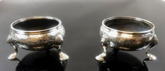 Scottish, English Silver Salts, 1805, 1790 (2pc): Pair of Sterling Silver George III Open Salt Cellars. Bowl form with tripod legs. Hand chased foliate decoration, bases with hallmarks for Scotland 1805 and England 1790. Both are in good condition, m