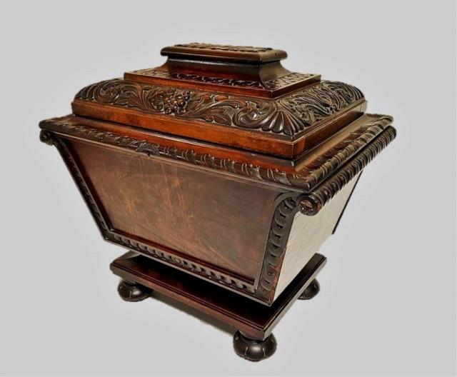19th C. English Carved Mahogany Cellarette: 19th C. English Carved Mahogany Cellarette. Profusely carved hinged lid with foliate and Neoclassical designs with canted coffin form. Interior lead lined with center drain. Excellent condition, measu