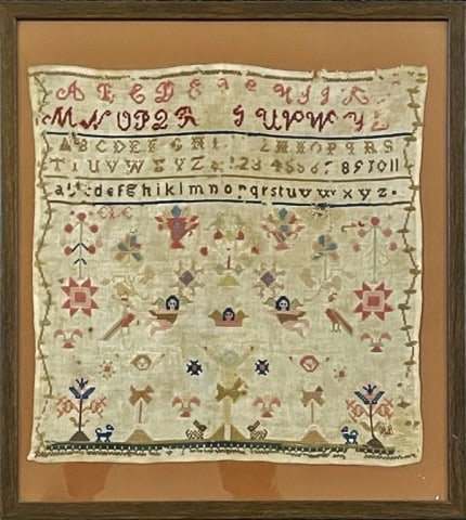 Circa 1800 American Needlework Sampler: Circa 1800 American Needlework Sampler. Crafted in multi colored thread with alphabet and various design elements including at bottom crucified Christ with angels above and flowers and animals includi