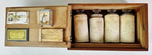 Antique Educational Exhibit, Baker Chocolate: Antique Educational Exhibit Kit, Baker Chocolate. Wooden box with plate, fitted interior containing four glass jars with stoppers. Lid fixed with tin and advertising pieces. Excellent condition, box m