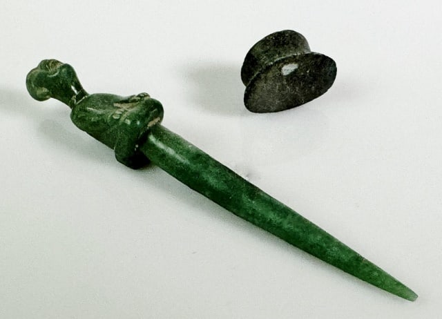 Pre Columbian Olmec Perforator, Chin Piece (2pc): Two Pre Columbian Olmec - Mayan Carved Jade and Stone Grave Objects: (1) Carved jade piercing implement with stylized seated figure with graduated shaft, measures: 4.75" L., (1) Carved stone button fo