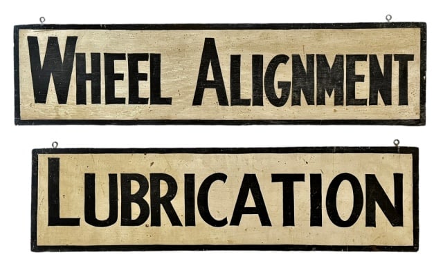 Antique Painted Wooden Automotive Signs (2pc): Two Antique Hand Painted Wooden Automotive Signs. Single sided white with black block letters "WHEEL ALIGNMENT" and "LUBRICATION". Signs are in good condition with wear, measure: 6.5" H x 25.5" W.