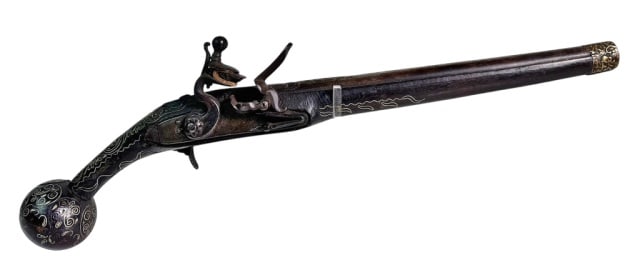 18th C. Balkan - Ottoman Flintlock Pistol: 18th C. Balkan or Ottoman Flintlock Pistol. Carved black walnut stock with profuse silver wire scroll decoration. Stock terminates with round ball butt. Steel flint lock and foliate decorated barrel. 