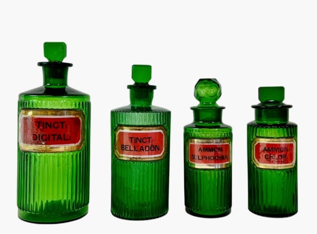 19th C. Green Glass Label Apothecary Bottles (4pc): Collection of Four 19th C. Glass Apothecary Bottles. Green blown glass with ribbed body and ground stoppers. Red foil labels under glass. Good condition with wear to glass label covers, largest measur