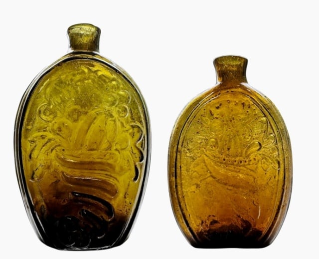 C. 1820 Glass Cornucopia Flasks, Keane NH (2pc): Two Early 19th C. Hand Blown Glass Flasks, Keene NH. Early Pint and half pint flasks in amber and olive color, embossed with cornucopia and urn decoration. Both with sheared lips and open pontil scars