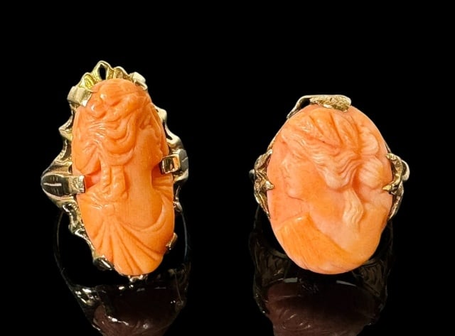 Antique 10K Gold Carved Coral Rings (2pc): Two Antique 10K Gold Carved Coral Rings: (1) Long oval shaped carved coral ring set in 10K gold band featuring a woman in profile with a flower in her hair facing right, (1) Stout oval shaped carved c