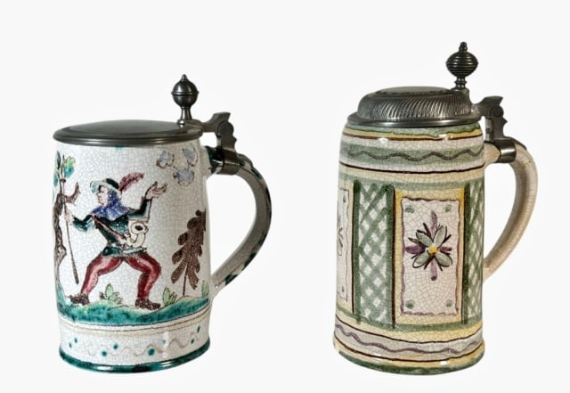 Antique German Hand Painted Faience Steins (2pc): Two Antique Hand Decorated German Faience Steins: (1) Stein with hand painted scene of hunter in traditional costume and deer with hinged pewter lid (1) Hand decorated with geometric panels with flowe