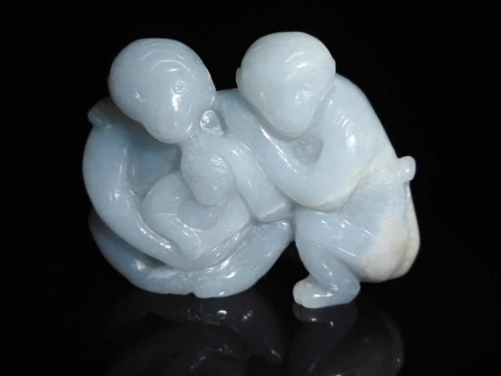 Jade Monkeys: Grey-white jade carving of two adult monkeys embracing a young monkey. Smooth polished surface with areas of white suffusion. 1.75" H
