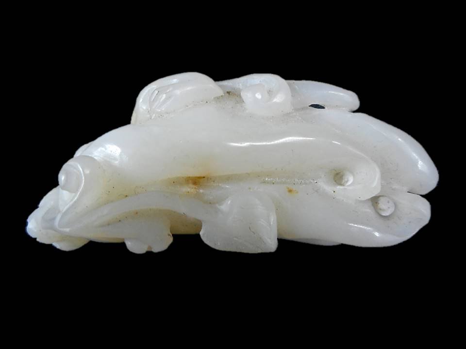 Jade Citron or Buddha's Hand Pendant: White jade pendant suspended by a red silk cord in the form of a citron or Buddha's Hand surmounted by a chilong incised details. Smooth finish with several areas of light yellow suffusion. 3"L