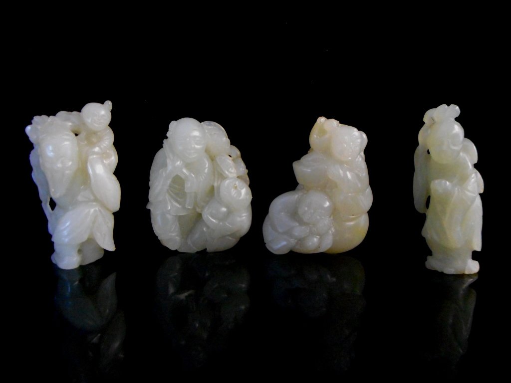 Four Jade Scholar Figures: Four white and green-white jade carvings in the form of monks, young boys and Shoulao, God of Longevity. Each having a smooth polished finish with incised details. Brown suffusion visible on the back 