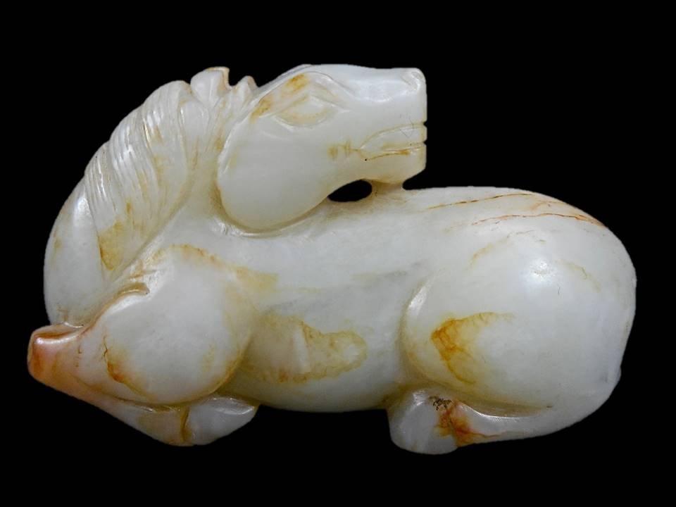 Jade Horse Figure: White jade carving of a recumbent horse with head turned backwards. Smooth polished surface with incised details, white, russet and black suffusion with areas of russet colored veining. 2.25"H x 4"W.