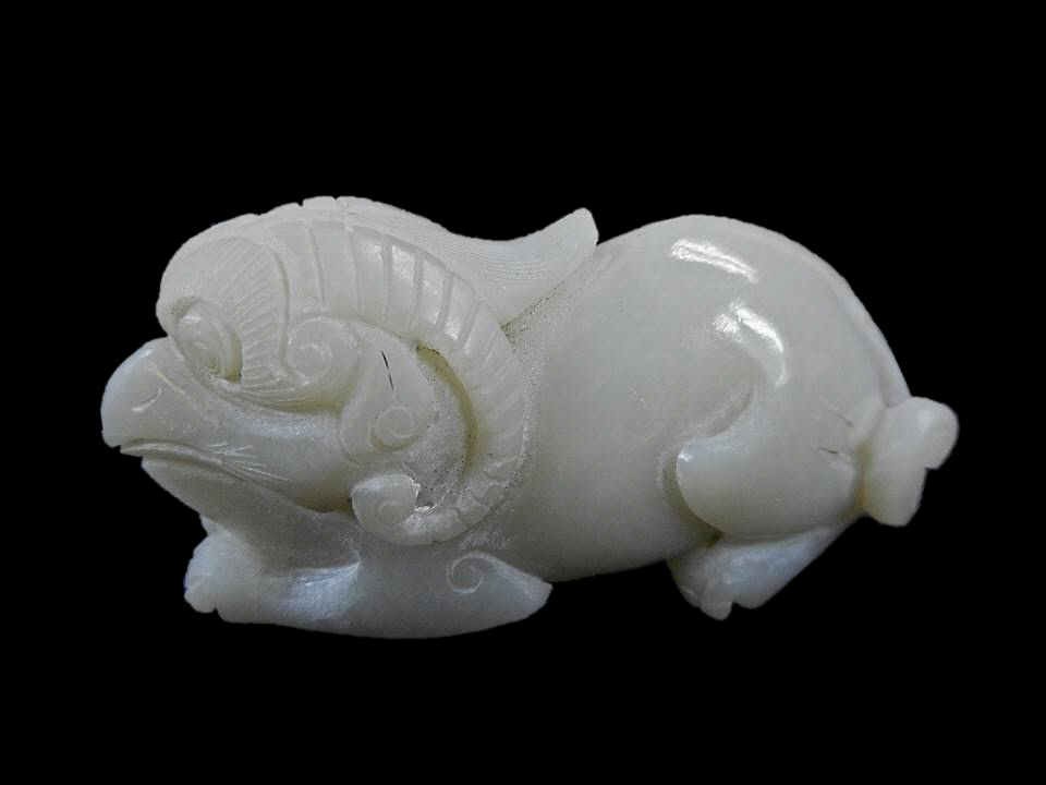 Jade Mythological Beast Figure: White jade carving of a recumbent mythological horned beast having the head of a bird. Smooth polished surface with incised details. 1.25"H x 2.5"W