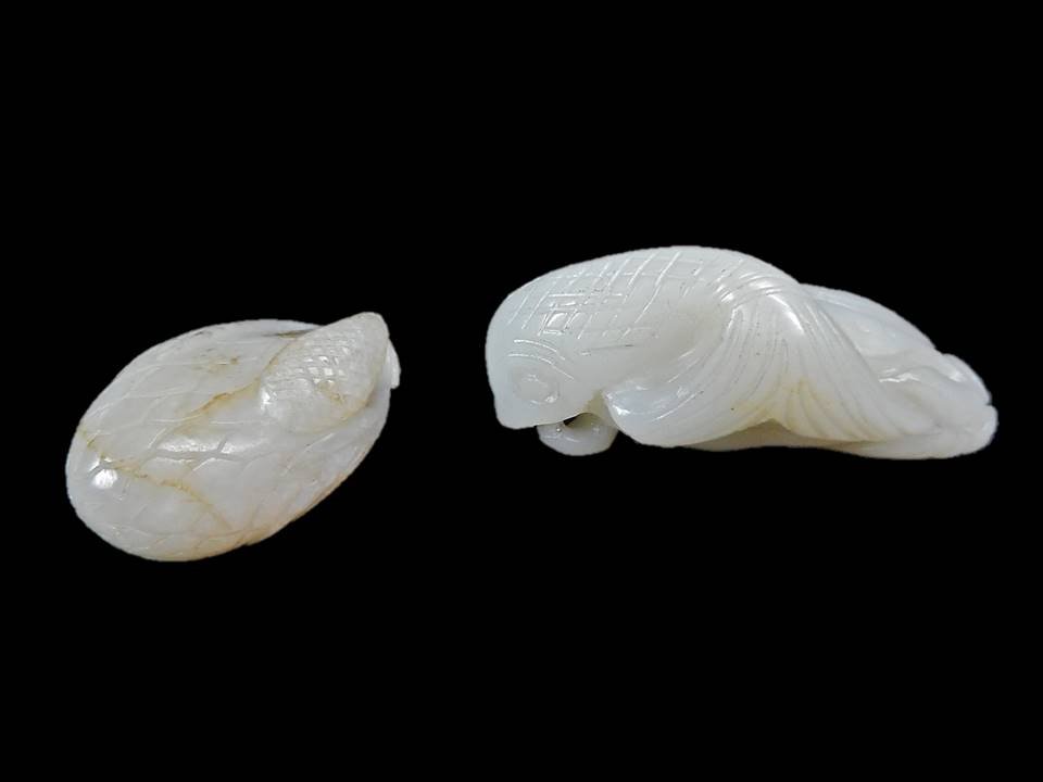 Two White Jade Figures of Fish and Fruit: Two white jade carvings having smooth polished surfaces with incised details. One in the form of a durian fruit or lotus pod with openwork carving at stem, and areas of dark brown suffusion. 1.5"H Tog