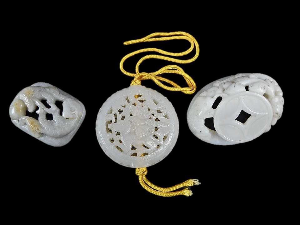 Three Jade Figures: Collection of three white jade openwork carvings: one of ovoid form in white jade, having a smooth polished surface, depicting a three-footed toad, coin and a chilong. 2.5"L x 1.75"W_x000D_ Together w