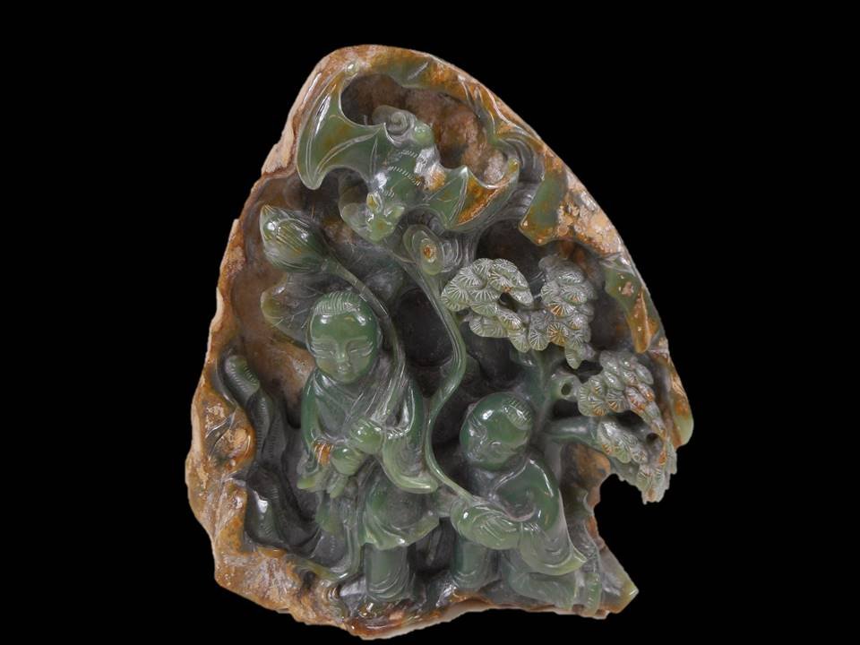 Jade Openwork Carving: Green jade carving in natural stone of two young boys with lotus fronds, a pine tree and bats. Auspicious symbol is carved on reverse. Smooth polished surface with natural stone rind suffusion. Calcif